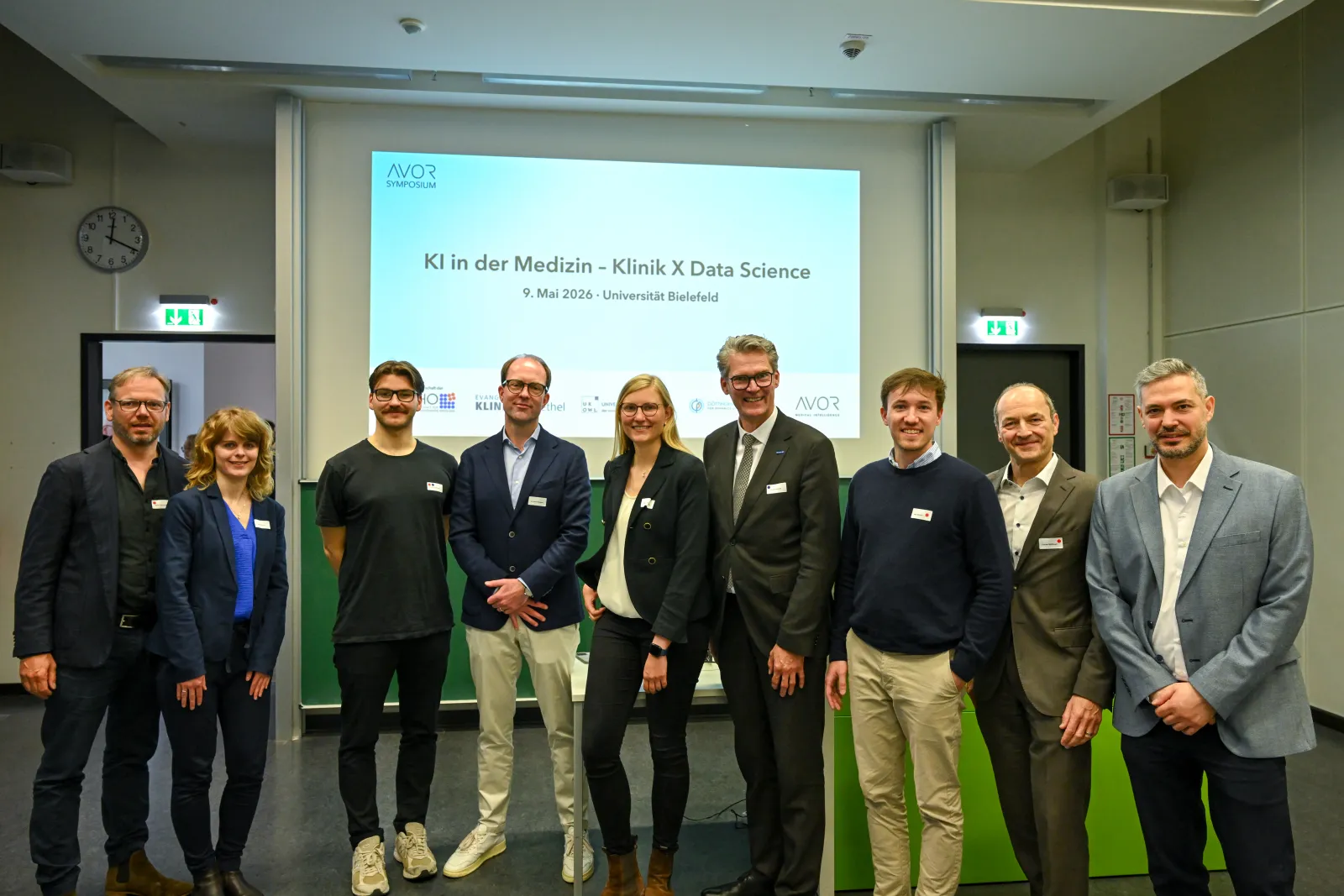 Gruppenfoto von Organisations- und Sprecherteam vor der Eröffnungsfolie