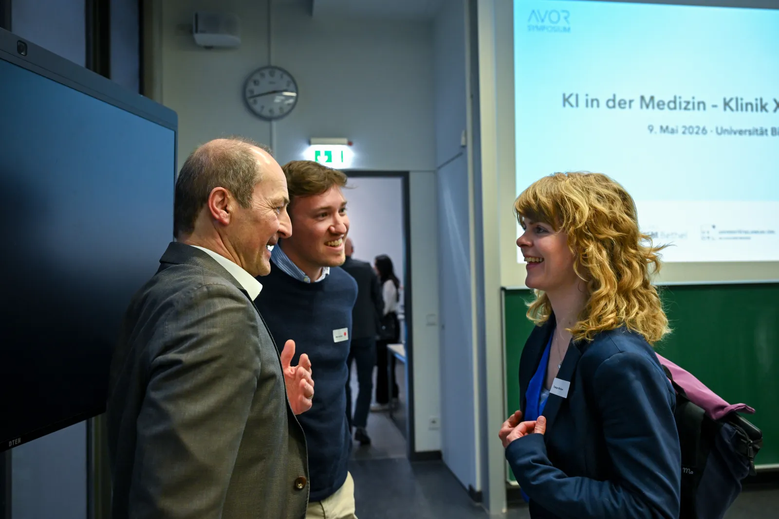 Drei Teilnehmende im Gespräch vor der Eröffnungsfolie